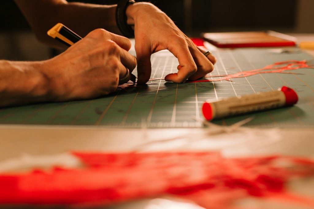 Hands using a craft knife to cut precise shapes for a DIY paper model kit