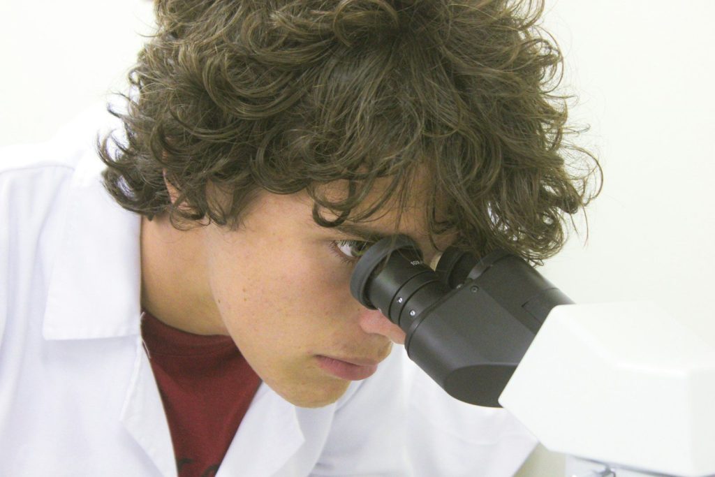 A young scientist using kids microscope and biology kits for discovery in a home lab