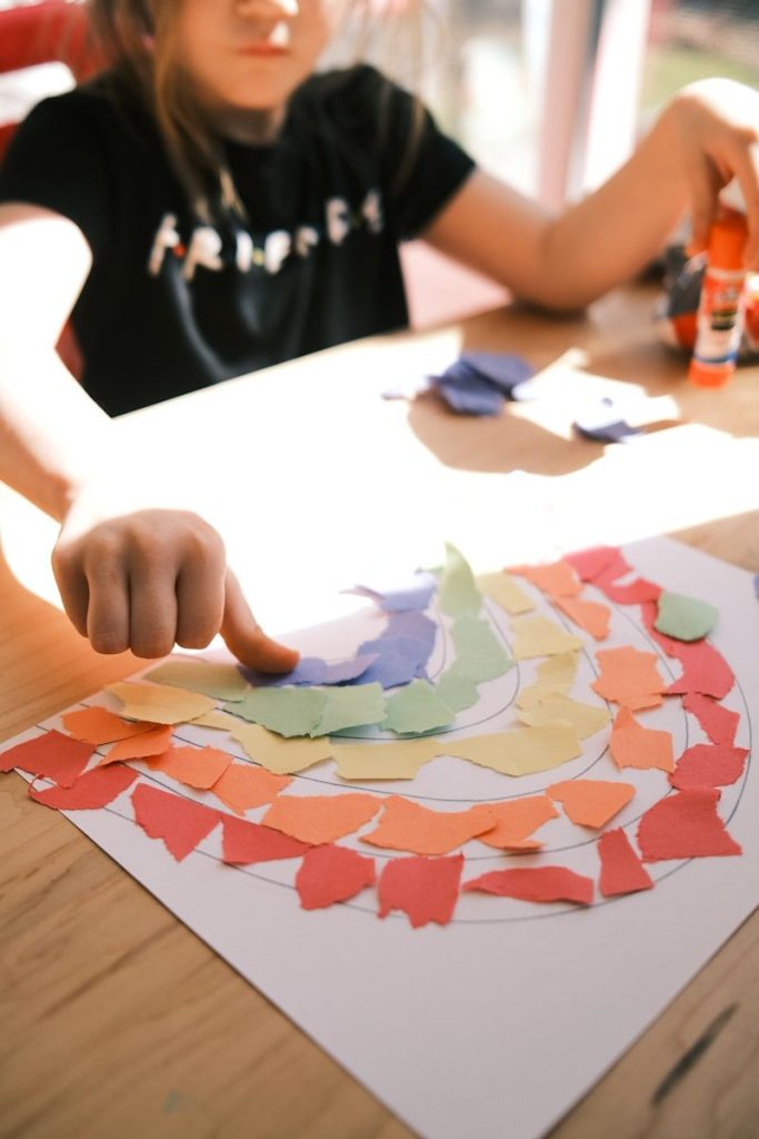 A child meticulously folding and gluing a colorful paper model